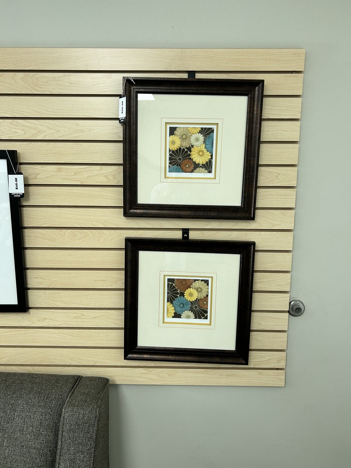 Two matching framed botanical prints in dark frames displayed on slatwall
