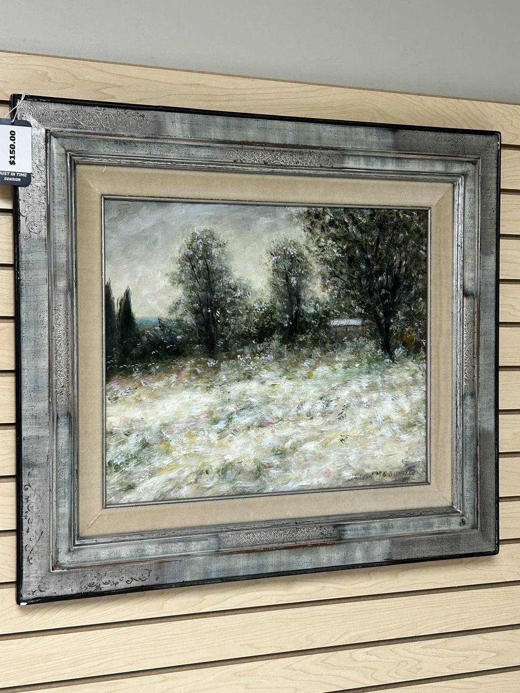 A framed winter landscape painting of snow-covered trees in a distressed silver frame